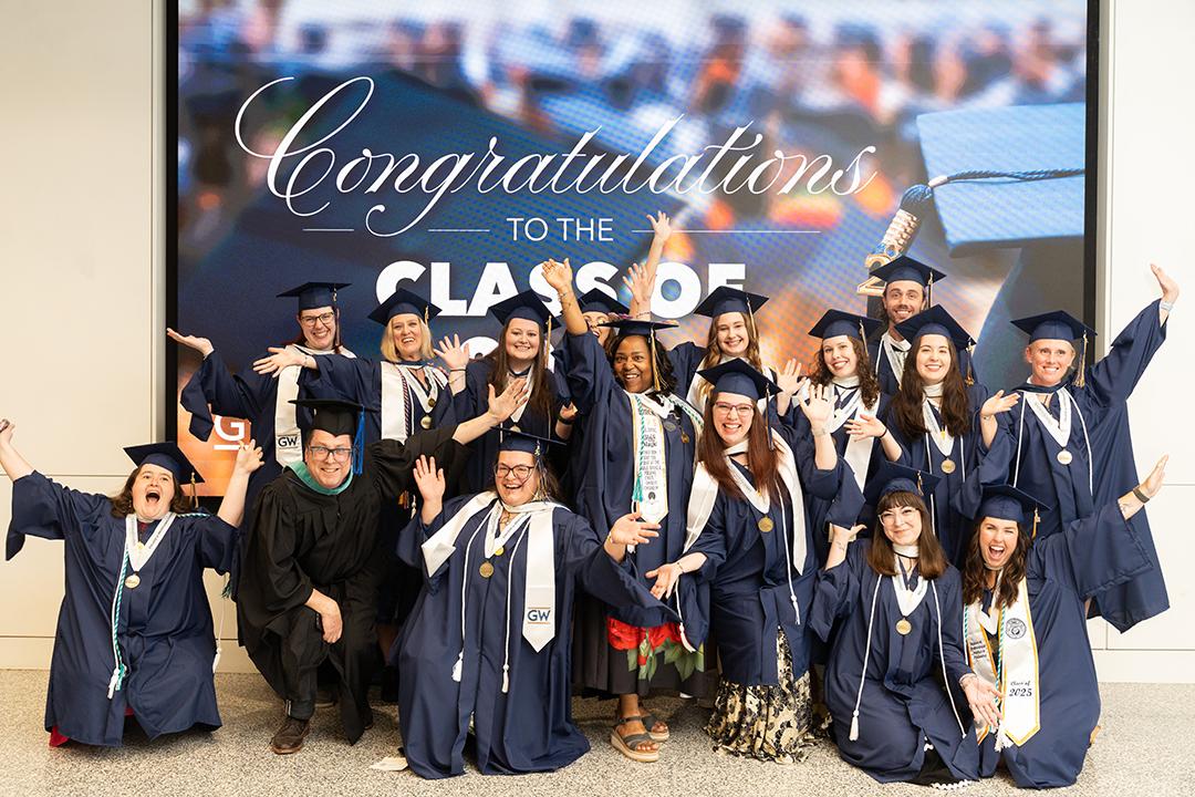 Student graduates pose in a group with regalia